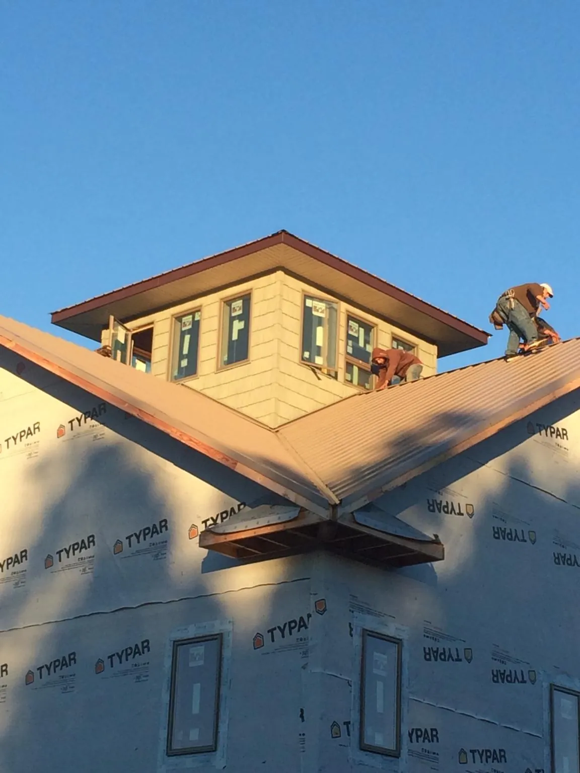 Roofers working around a rooftop cupola on a new metal roof at sunset — Roof Waterproofing in Columbia by Roofing Brothers